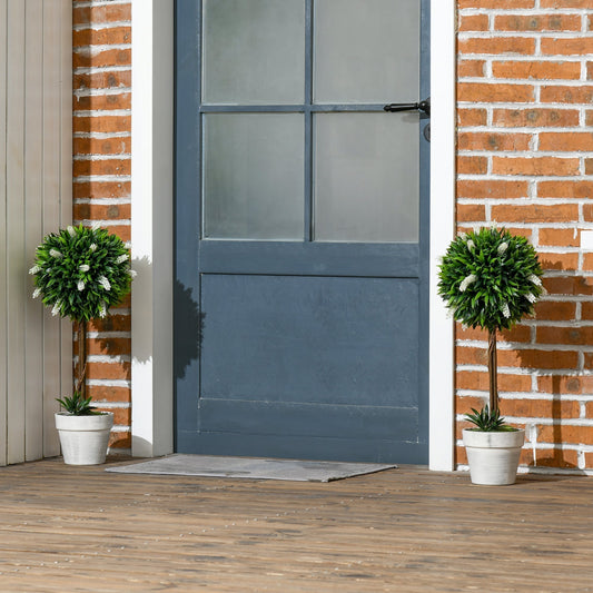 Two decorative artificial plants ball trees in pots placed outside a blue door on a wooden porch