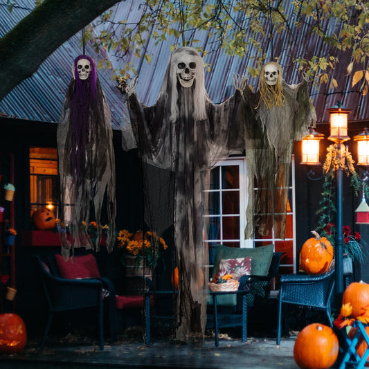 Three hanging skeleton Halloween decorations displayed outdoors on a patio with pumpkins and chairs
