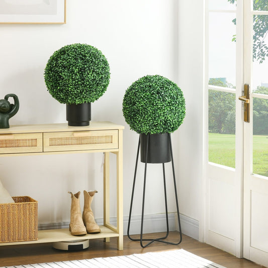 Two artificial boxwood ball plants in black planters on a console table