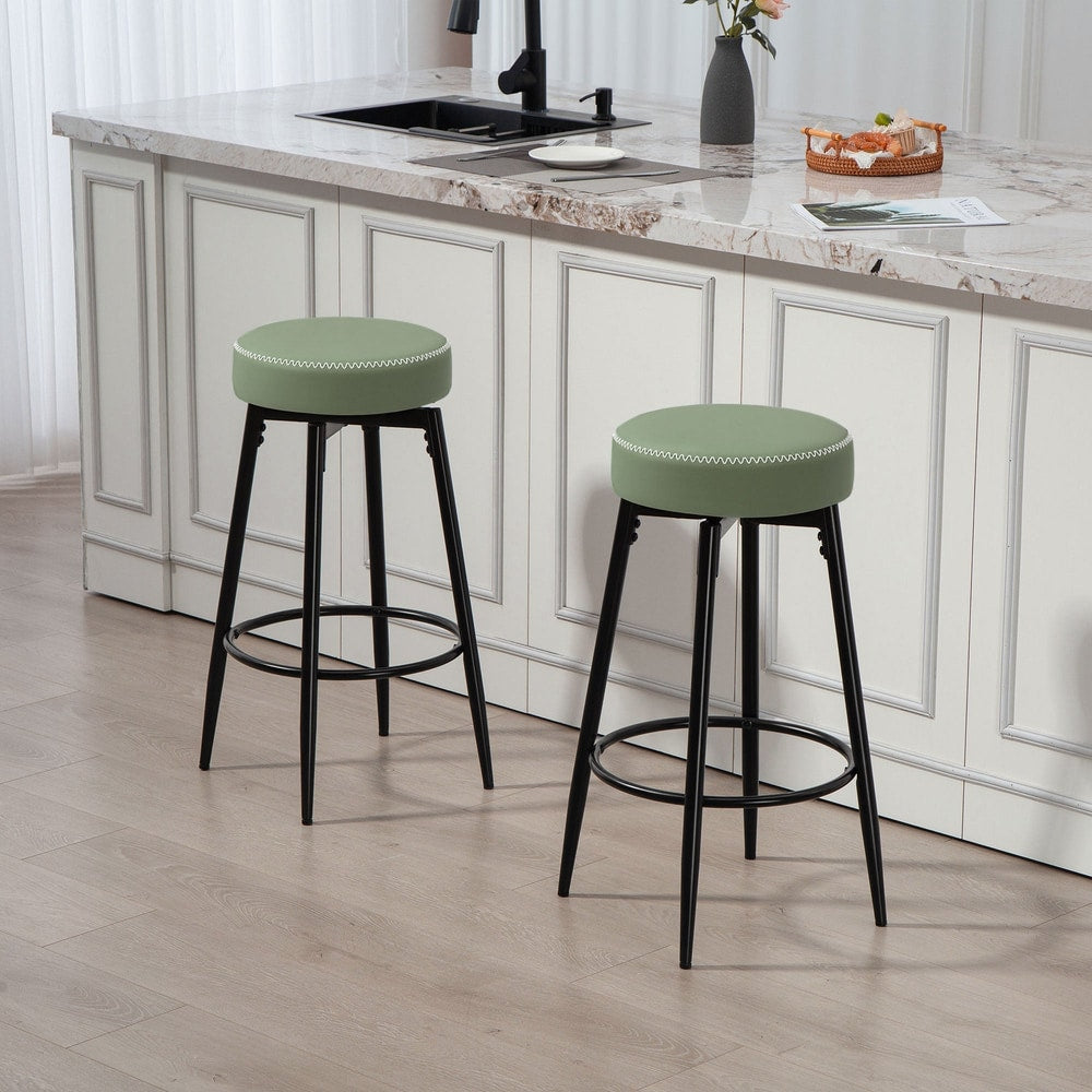 Two green faux leather bar stools in a modern kitchen setting
