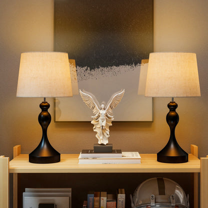 The table lamps placed on a wooden shelf with a decorative angel statue between them in a living room