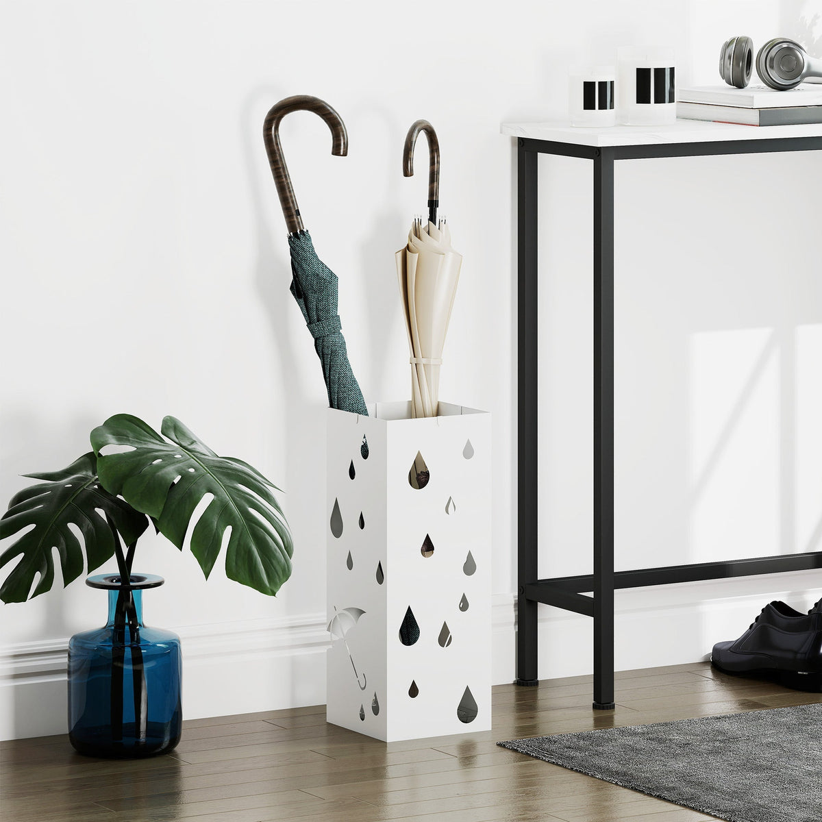 The umbrella stand holding two umbrellas in a bright hallway next to a house plant