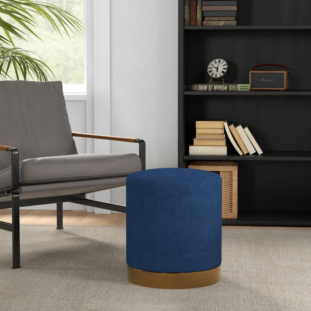 Dark blue corduroy footstool placed next to a grey armchair in a living room