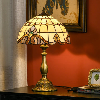 The stained glass lamp sits on a dark bedside table next to a small picture frame