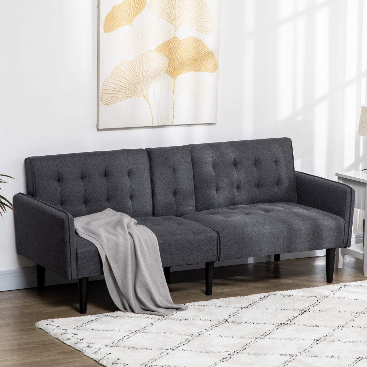 Grey sofa bed with a blanket draped over the armrest in a living room setting