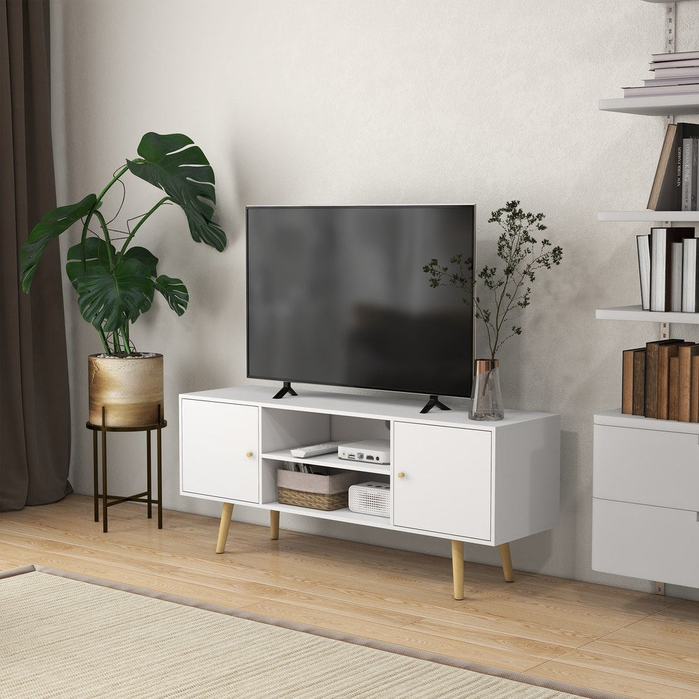The TV unit with storage shelves and wood legs in a modern living room with a TV and plant