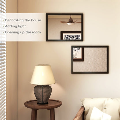 Two black framed wall mirrors hanging on a wall above a lamp and chair