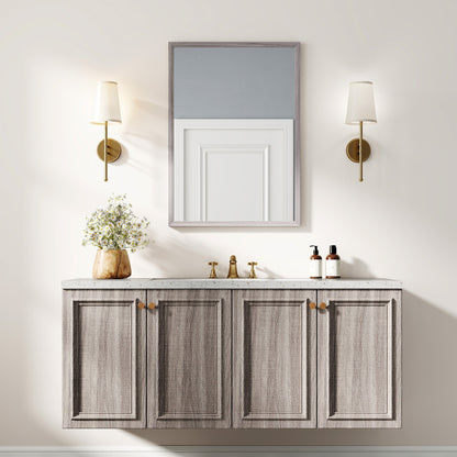 The wall mirror is mounted above a grey vanity with two sinks and brass taps