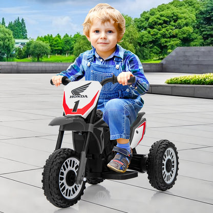 Toddler sits on the grey kids electric motorbike on a paved area