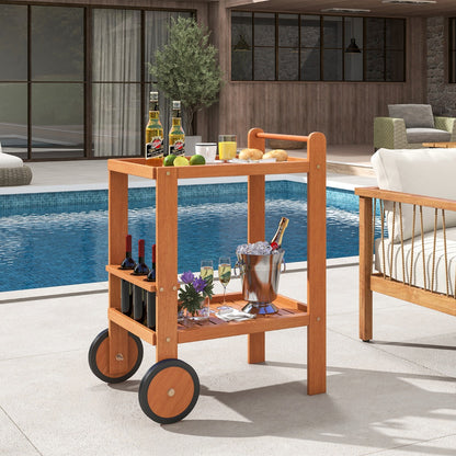 The wooden bar cart holding wine and glasses by a swimming pool on a patio