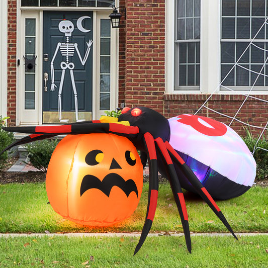 The Halloween spider decoration is inflated next to a pumpkin on a lawn