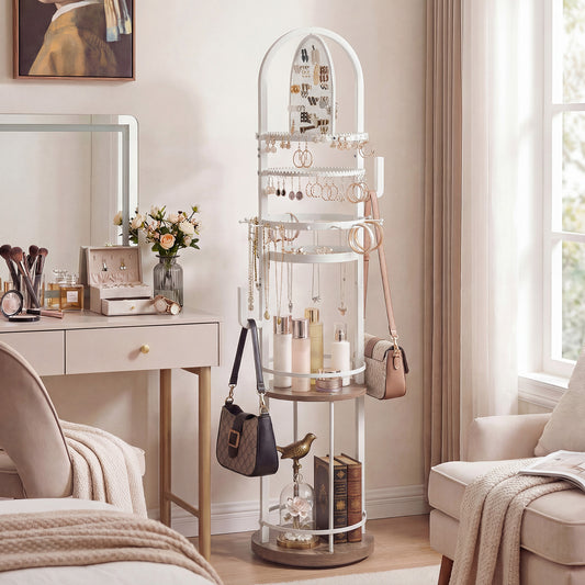 The jewelry armoire standing in a bright bedroom next to a dressing table and armchair
