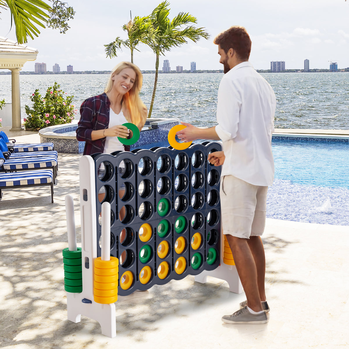 Couple playing the giant four-in-a-row lawn game by a swimming pool