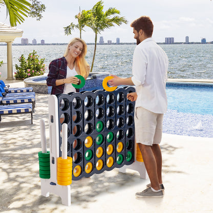 Couple playing the giant four-in-a-row lawn game by a swimming pool