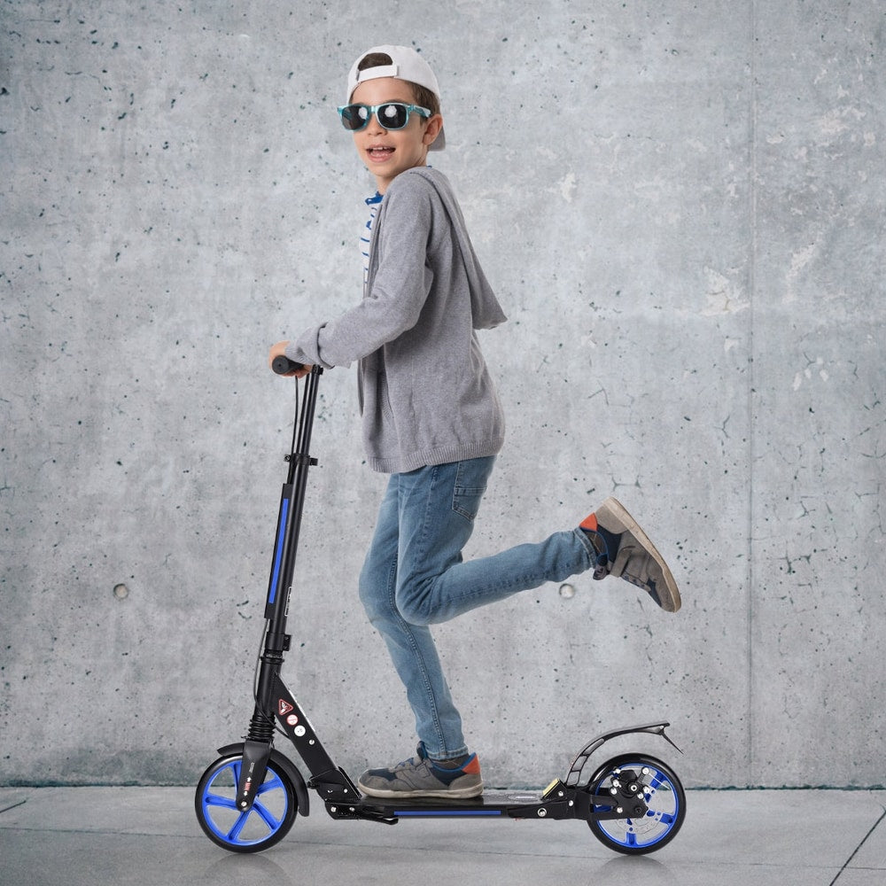 The kick scooter being ridden by a young boy wearing sunglasses and a grey hoodie