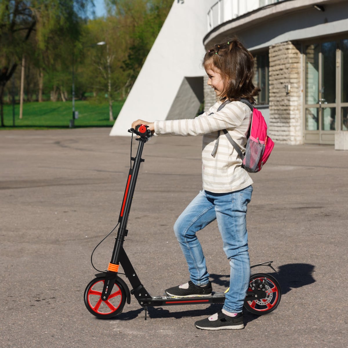 A girl with a backpack riding the black kick scooter with red wheels on a pavement