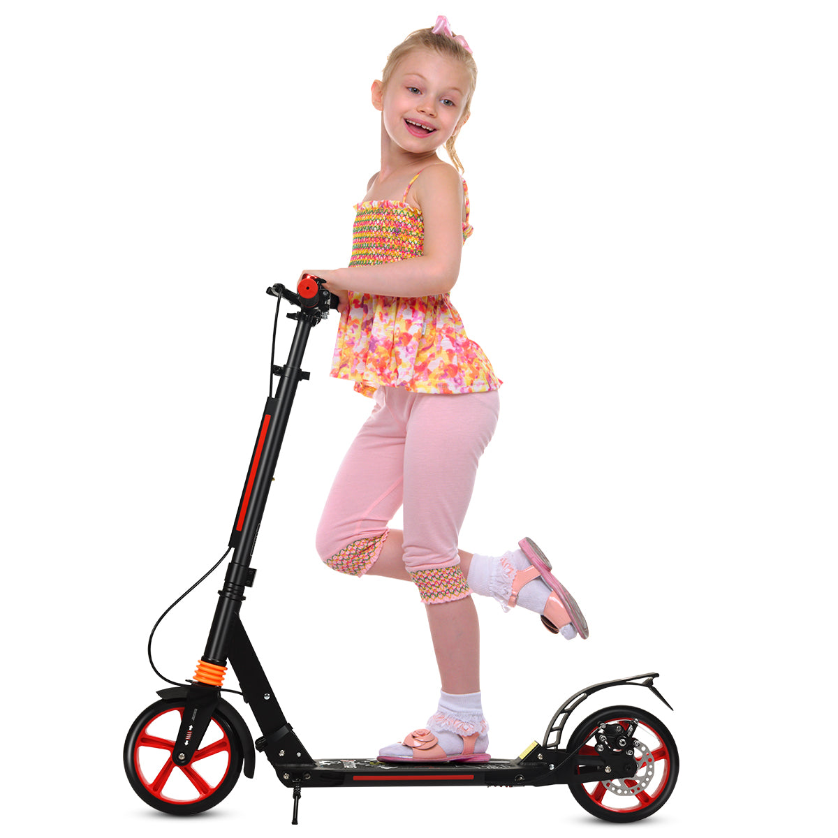A girl poses on the red kick scooter against a white background
