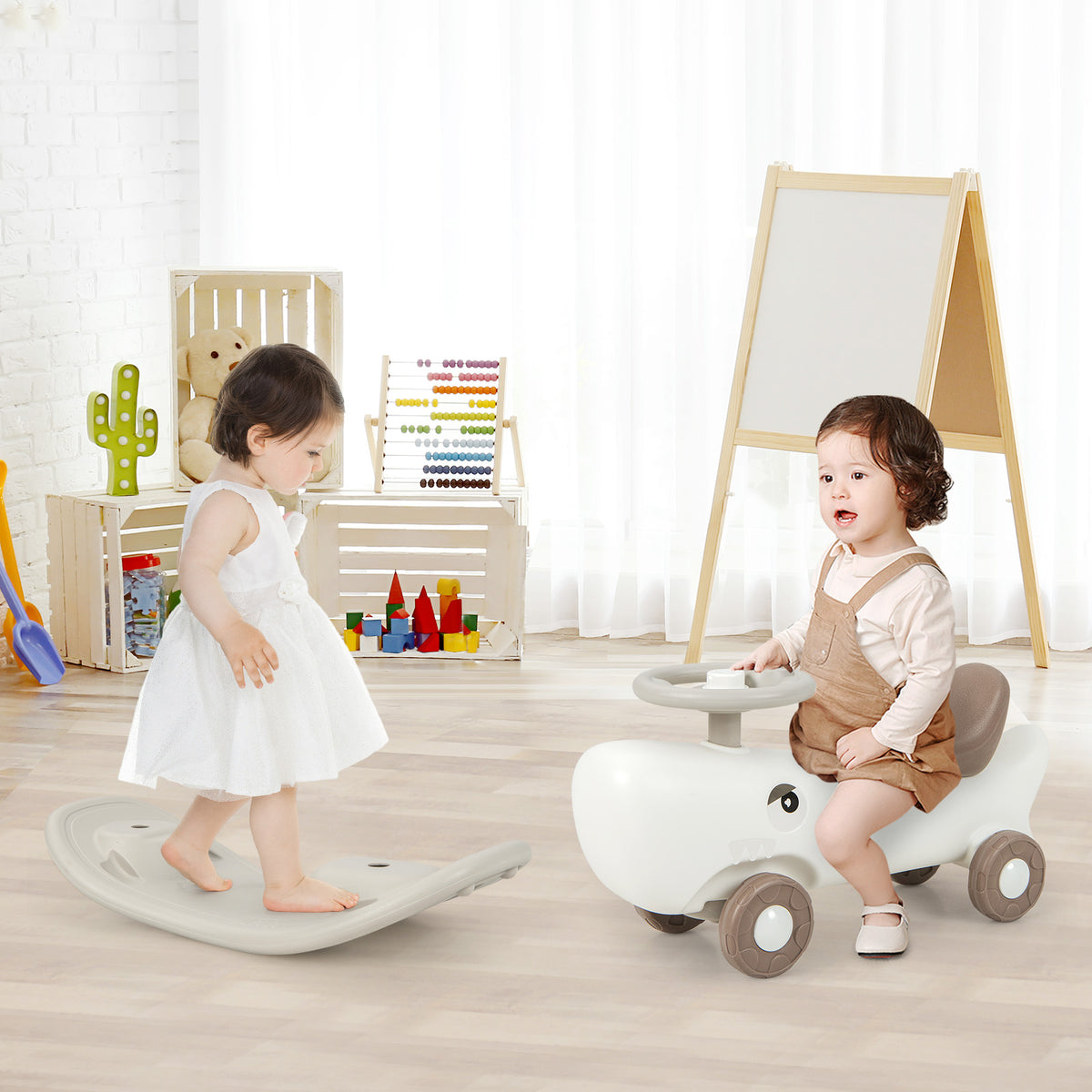 A white convertible rocking horse and sliding car with a child on it, next to a balance board in a playroom