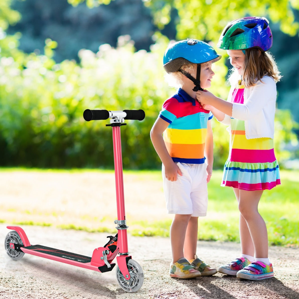 The pink stunt scooter standing on a path next to two children wearing colourful helmets