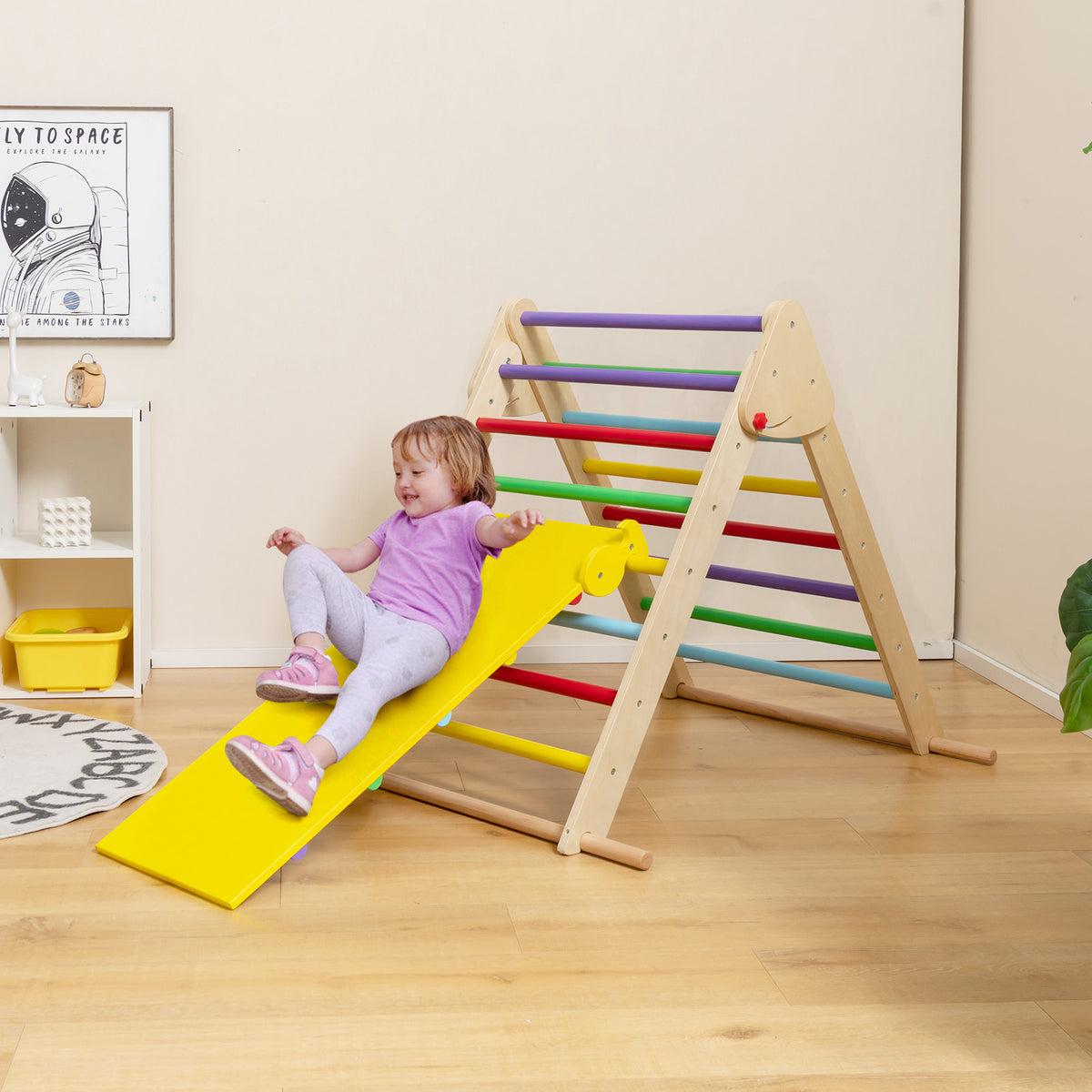 The climbing frame is set up in a child's room with a girl sliding down the ramp