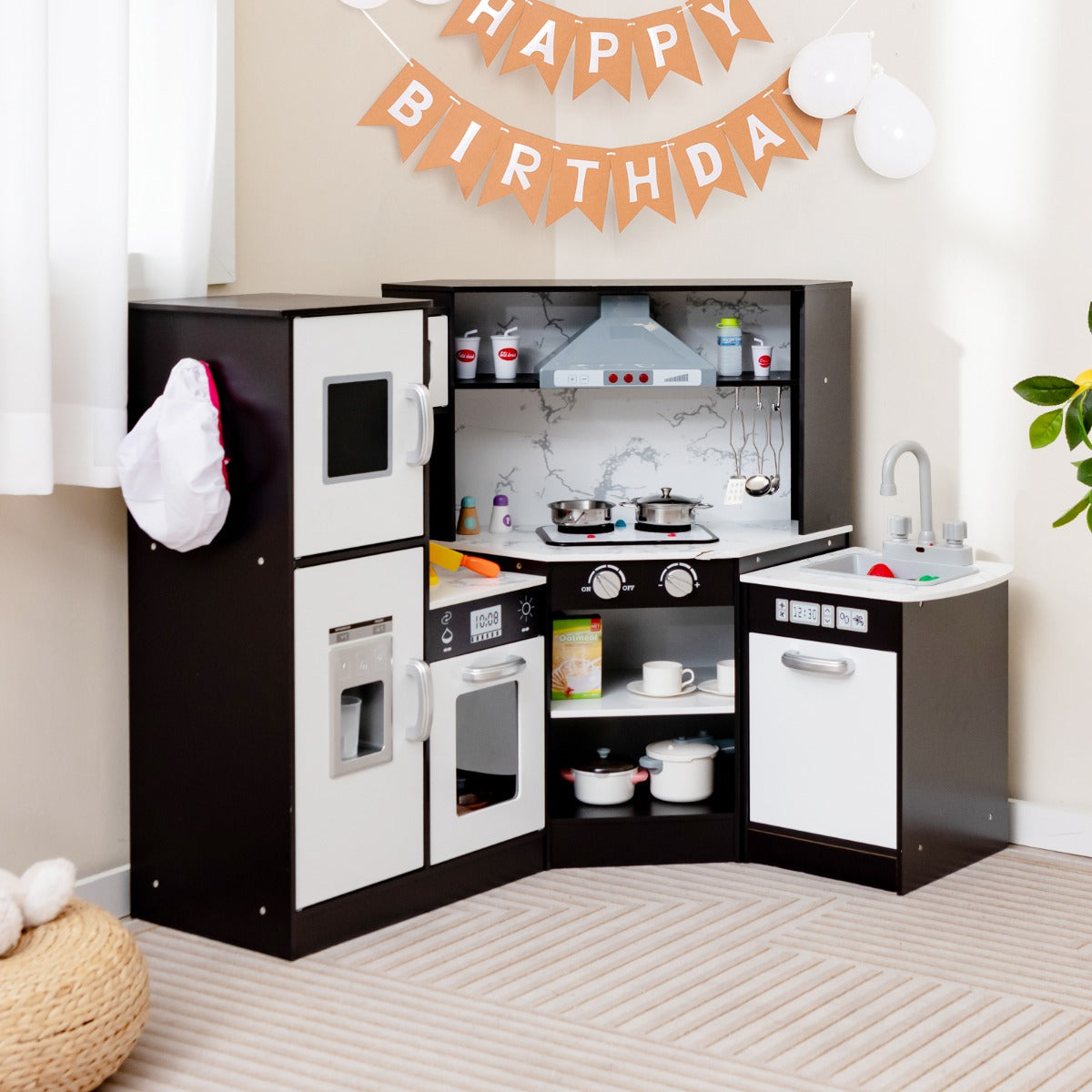 The play kitchen set placed in a corner of a room with birthday decorations