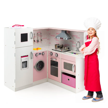 A girl in a chef hat and apron stands next to the corner play kitchen