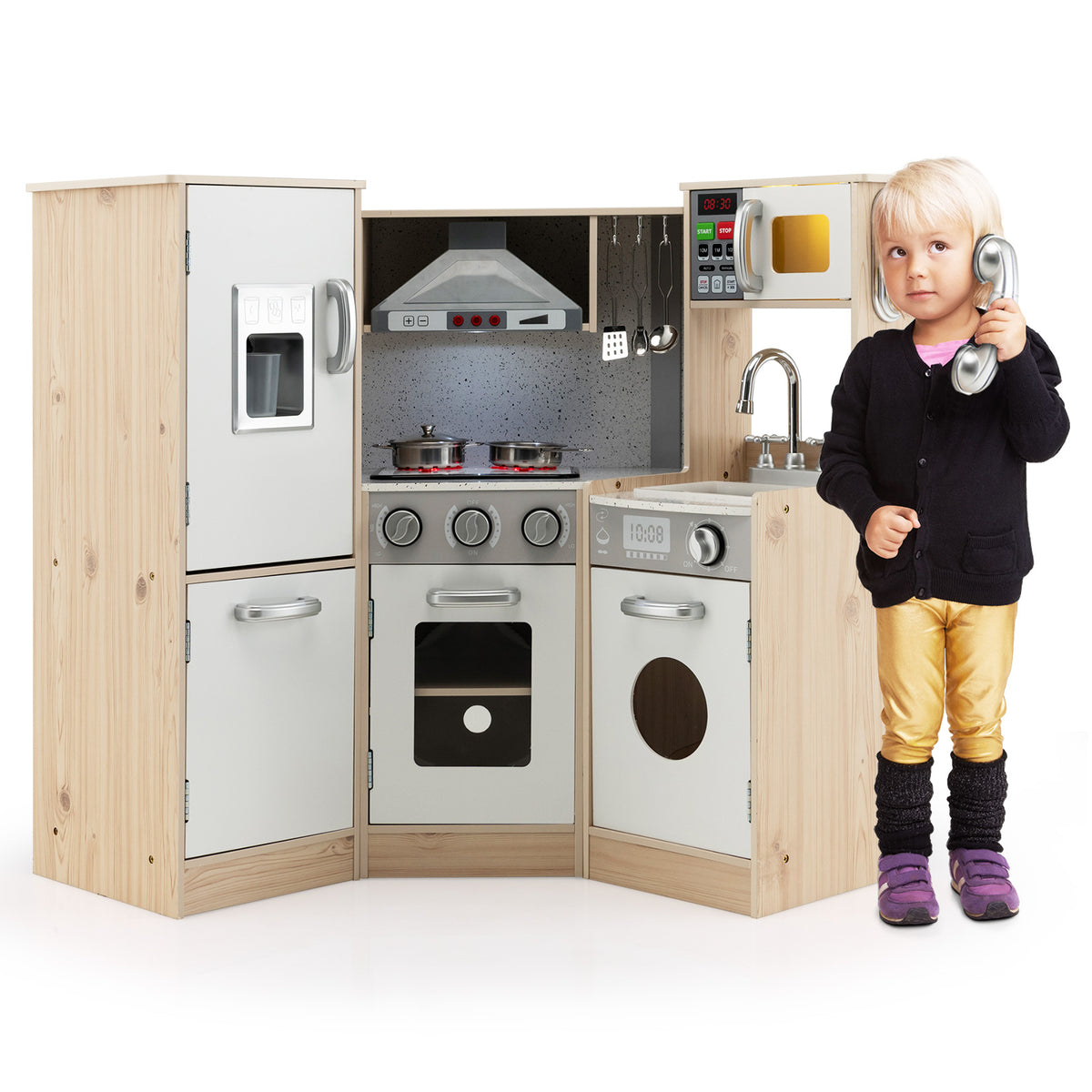 A young girl holds a toy phone to her ear while standing next to the wooden kitchen playset