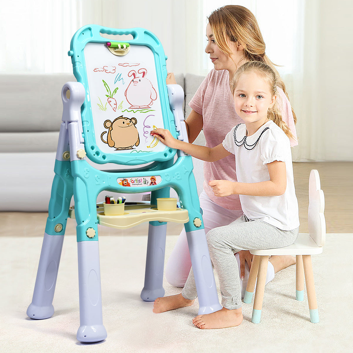 A mother and daughter drawing together on the green kids art easel in a living room