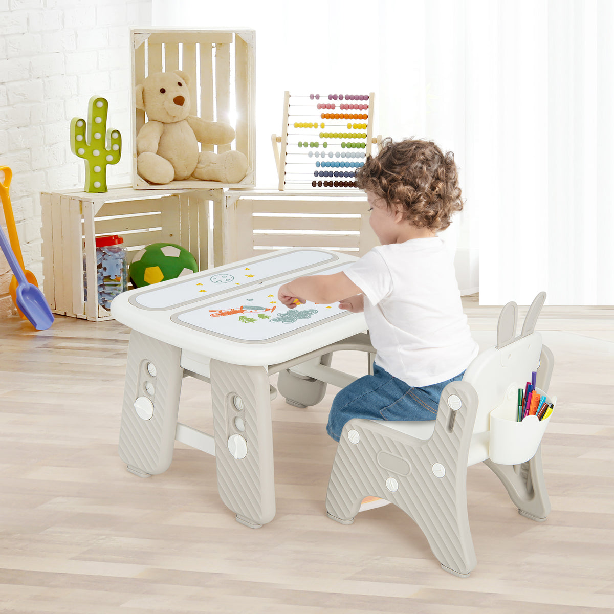 Child sitting at the kids drawing table and chair set with books and toys on the shelf