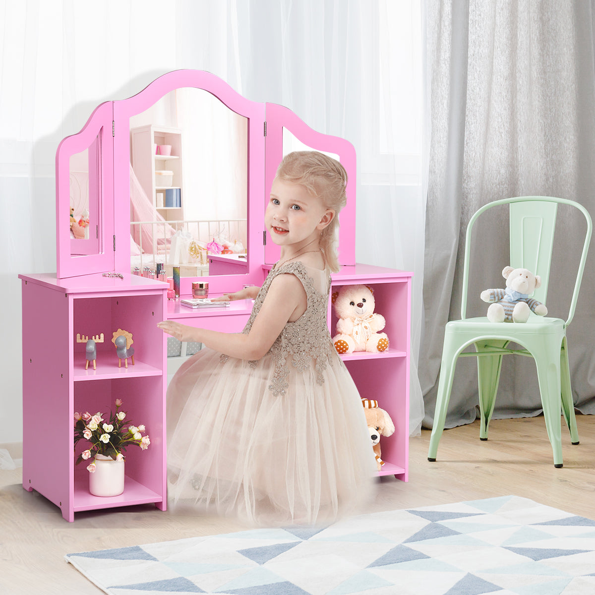 A young girl in a dress playing at the pink kids vanity table with mirror