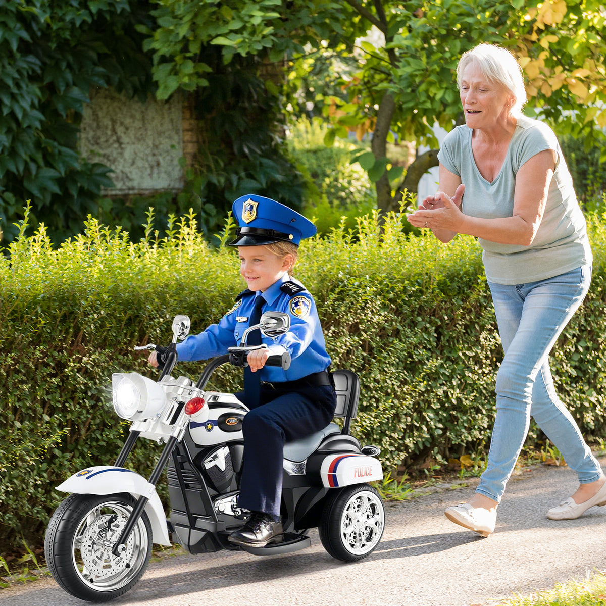 The kids electric motorbike being ridden by a child in a police uniform on a garden path
