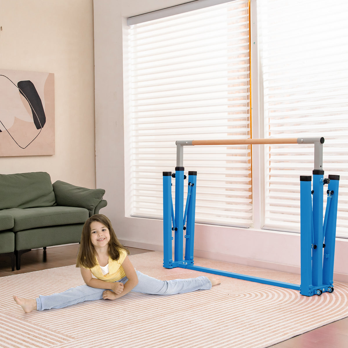 A young girl sitting in a split next to the blue kids gymnastics bar