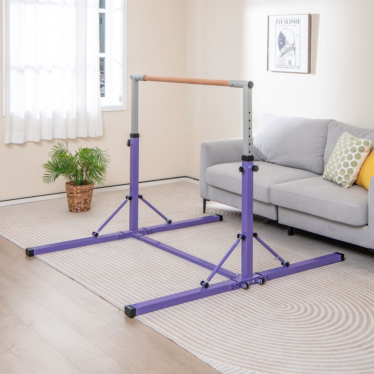 The gymnastics bar set up on a rug in a bright living room next to a grey sofa