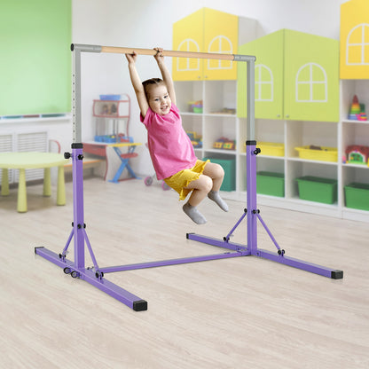 A young girl hanging from the wooden bar of the purple gymnastics equipment in a playroom