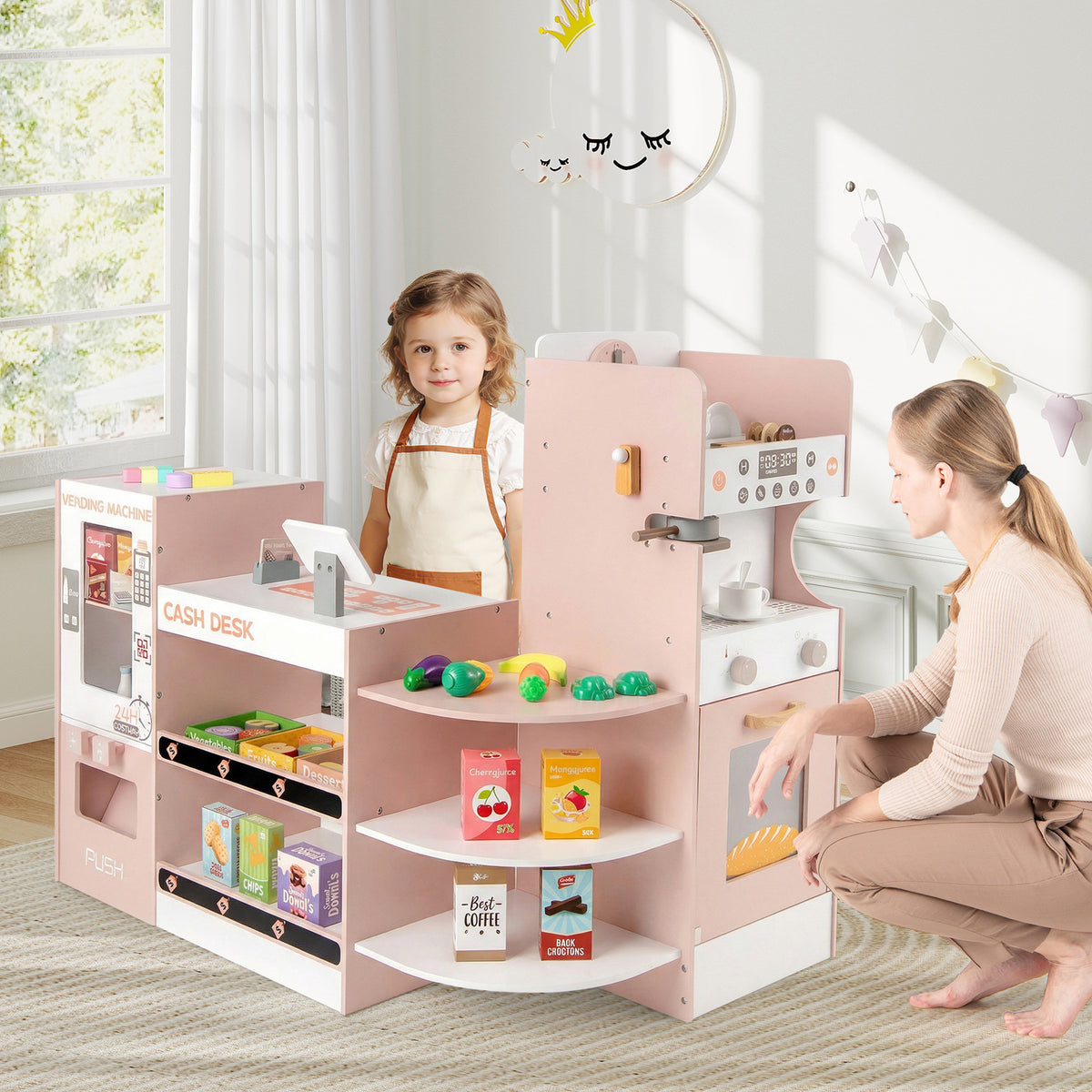 A young girl and a woman playing with the pink wooden grocery store playset