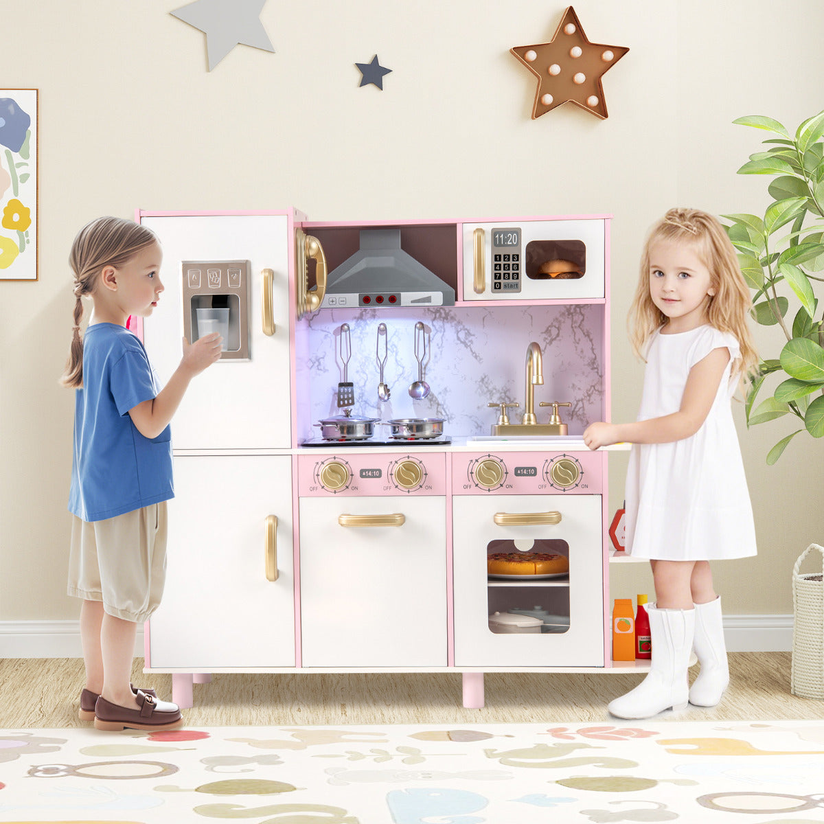 Two children playing with the pink wooden play kitchen set in a room
