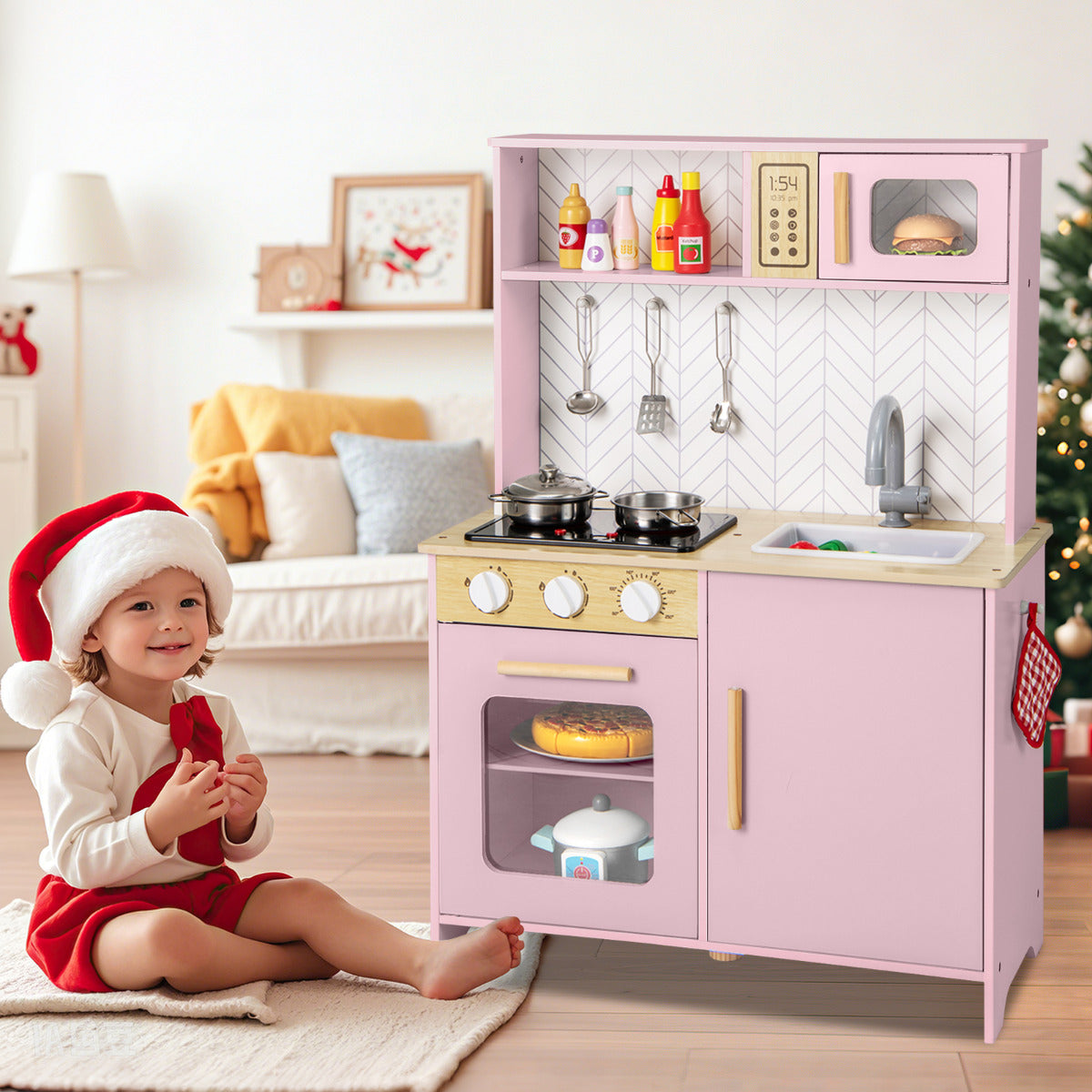 The play kitchen set beside a young child wearing a Santa hat in a festive living room setting