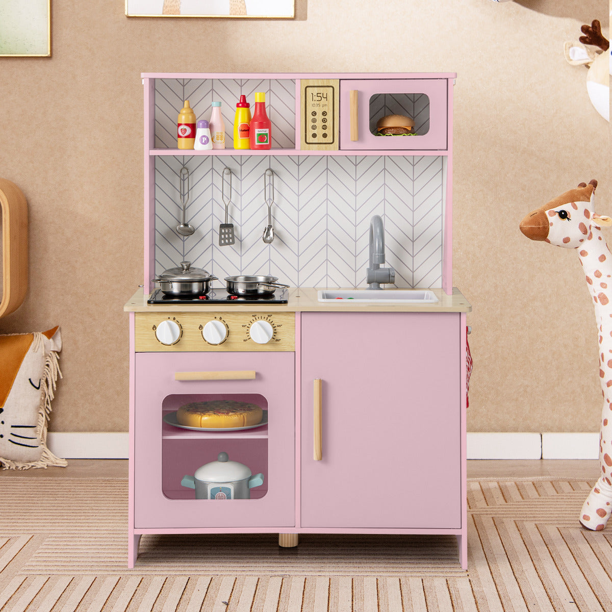 The play kitchen set standing in a child's bedroom next to a toy giraffe and patterned wallpaper