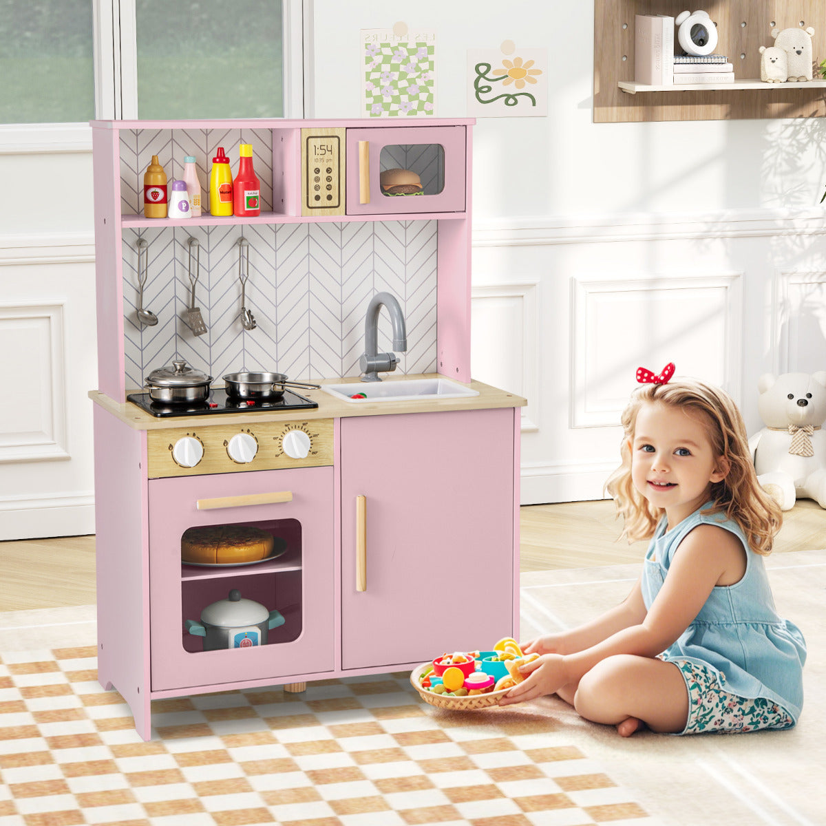 The play kitchen set in a bright room with a young girl sitting on a rug holding a basket of food
