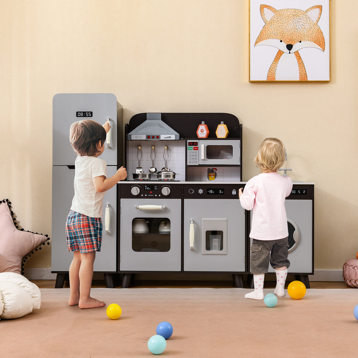 Two young children playing with the brown wooden play kitchen set with refrigerator and washing machine