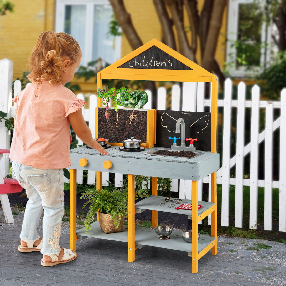 A young girl plays with the blue and yellow kids kitchen playset outdoors