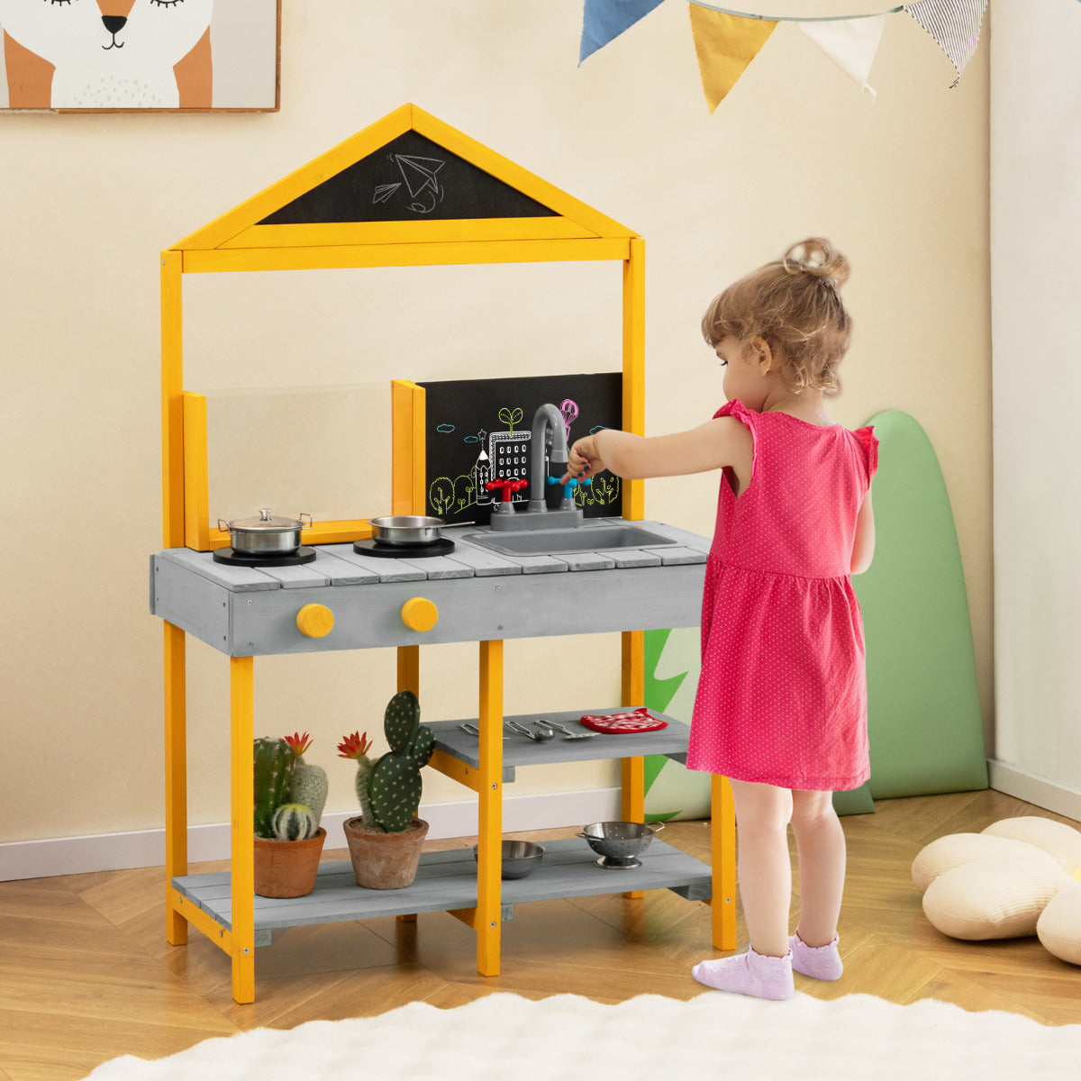 A young girl playing with the grey and yellow outdoor kitchen playset indoors