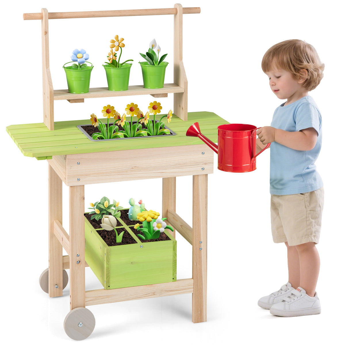A young child standing beside the play kitchen set holding a red watering can in their hand