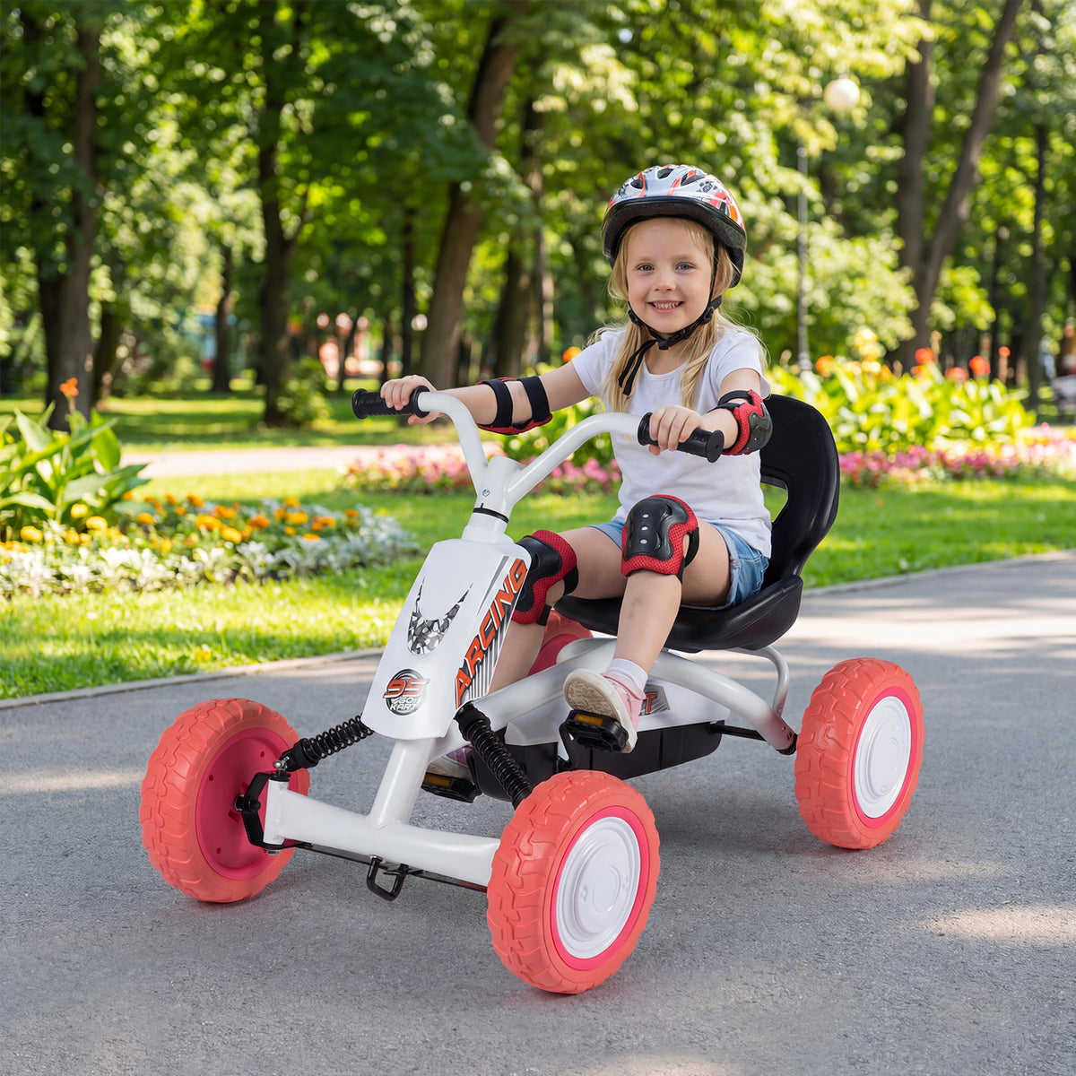 A girl smiles while riding the white pedal go kart in a park