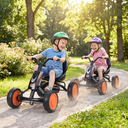 Two children riding the push and pedal ride on toys on a path in a park