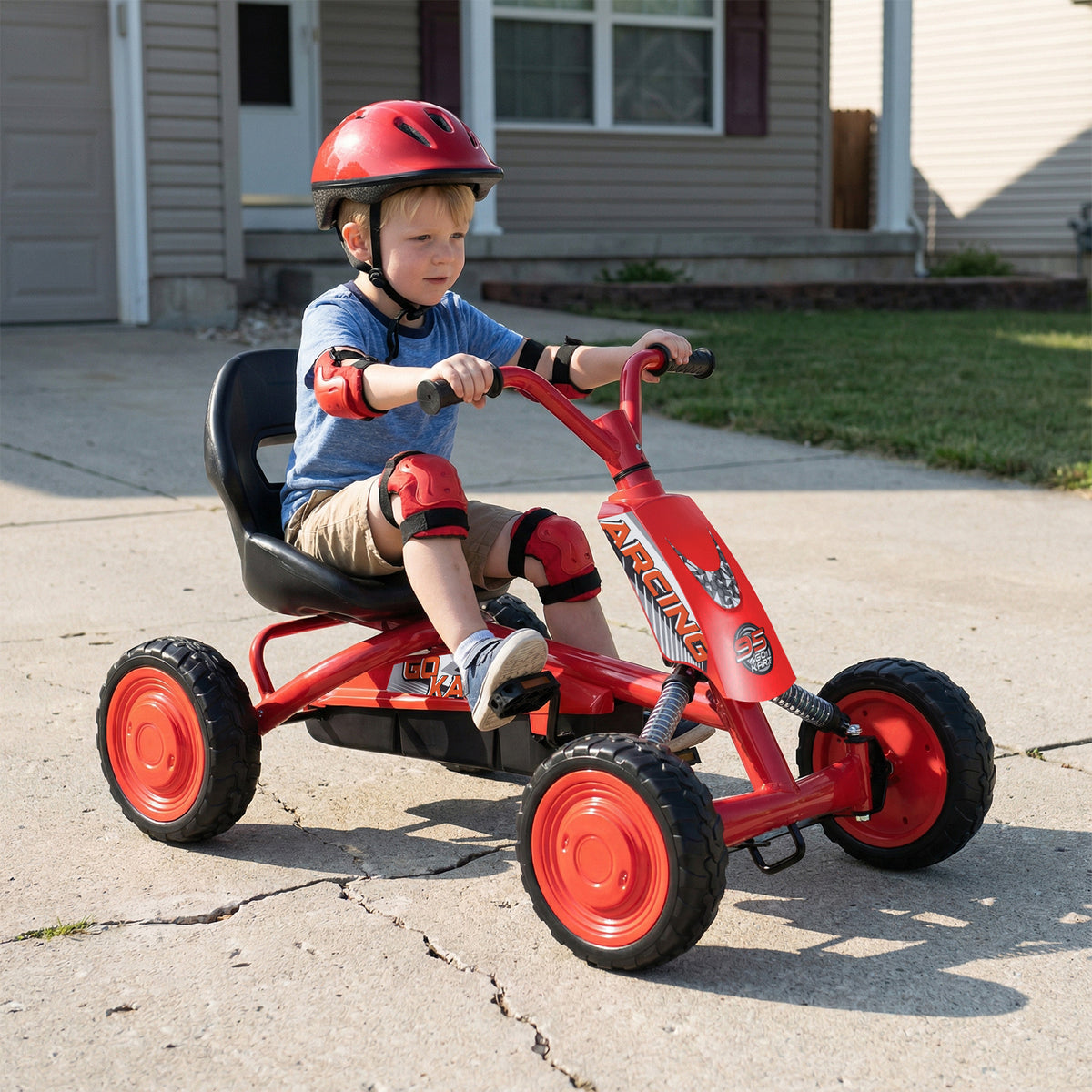 Boy driving the red pedal go kart on a paved driveway