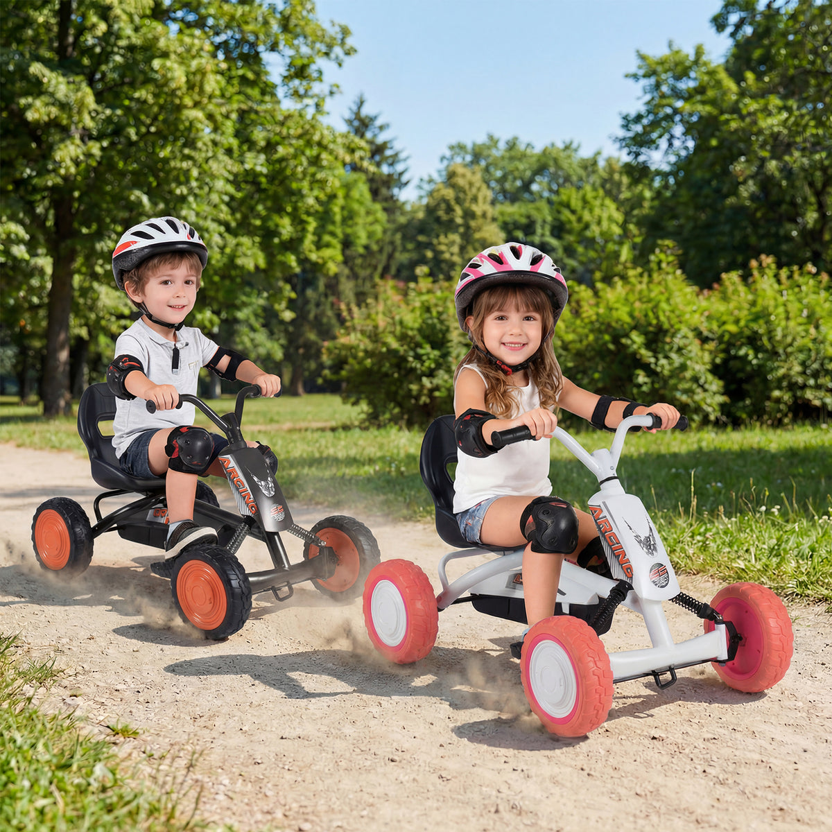 Two children wearing helmets ride pedal go karts in a park setting