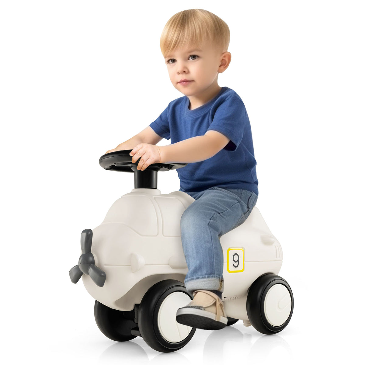 A young boy sitting on the push and pedal ride on toy in a bright indoor setting