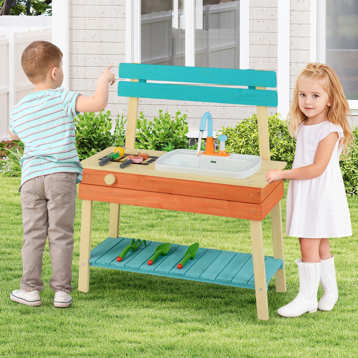Two children playing with the wooden kitchen playset in a garden setting