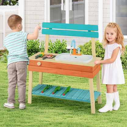 Two children playing with the wooden kitchen playset in a garden setting